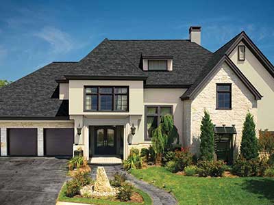 Front view of a mid-class, two-story beige home with black GAF shingles on its roof
