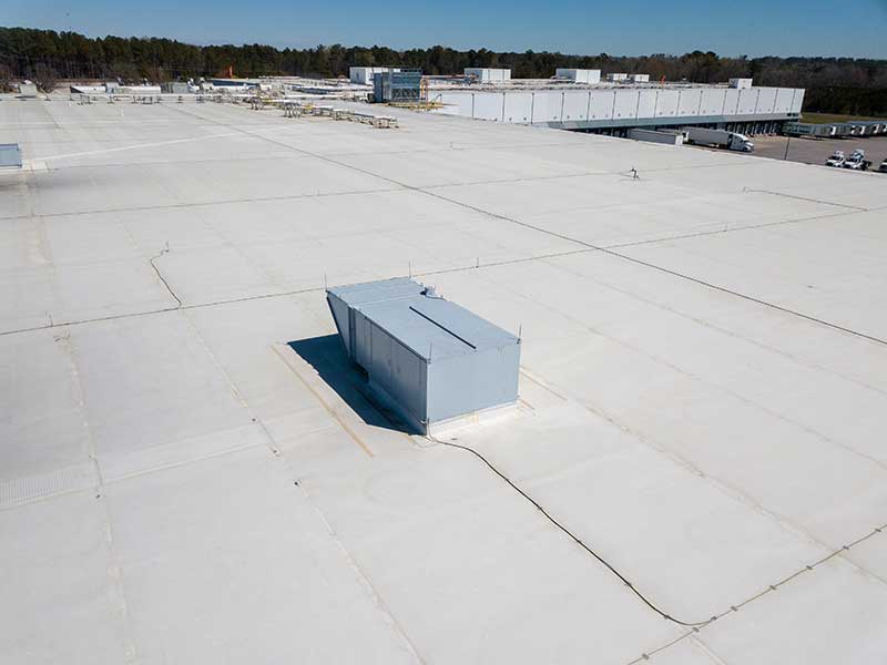 Overview of a flat, white commercial roof over a huge warehouse